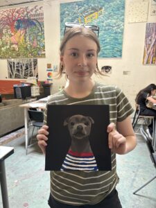 Girl showing painted dog portrait.