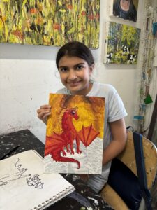 Girl proudly displays her dragon painting.