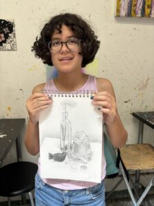 Girl proudly displays her still life drawing.