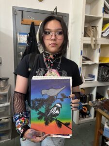 Teenager proudly displays bird painting.