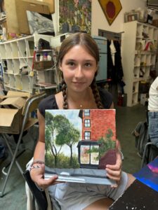 Girl proudly displays her painted cafe scene.