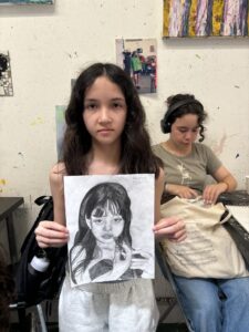 Girl proudly displays her charcoal portrait.