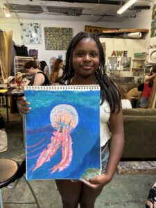 Girl proudly displays jellyfish drawing.