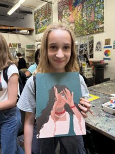 Girl holding self-portrait painting.
