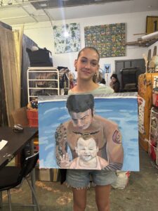 Girl holding painting of dad and baby.