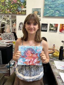 Girl proudly displays her fish painting.