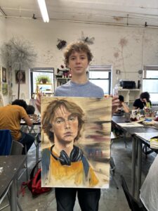 Student proudly displays his oil portrait.