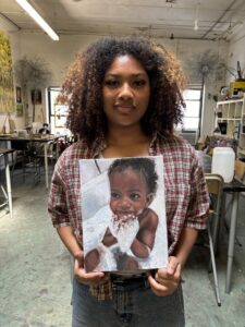 Artist holding a baby portrait painting.