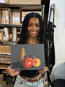 Young artist showing fruit still life painting.