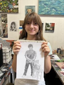 Girl holding pencil sketch of person.