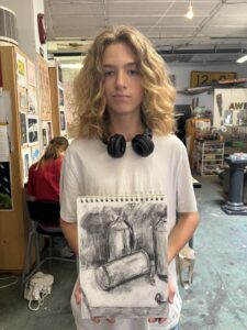 Teen showing charcoal still life drawing.