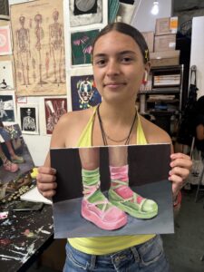 Girl holding painting of ballet shoes.