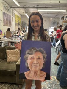 Student displays portrait painting of woman.