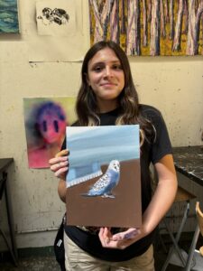 Girl holding painting of a parakeet.