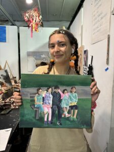 Student showing family portrait painting.