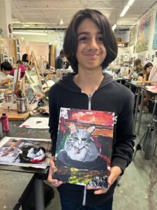 Boy proudly displays his cat painting.