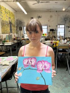 Teenager holding painted orchid artwork.