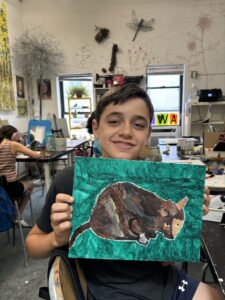 Boy proudly displays his cat painting.