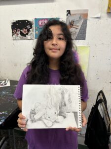 Girl proudly shows her still life drawing.