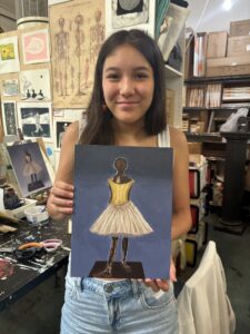 Girl holding ballerina painting.