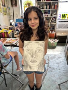 Girl proudly displays her pencil portrait.