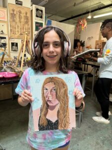 Girl proudly displays her painted portrait.