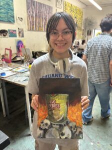 Girl holding painting of flaming Cup Noodles.
