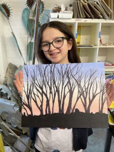 Girl holding sunset tree painting.