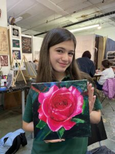 Girl proudly displays her rose painting.