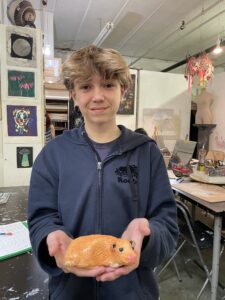 Teen showing off clay hamster sculpture.