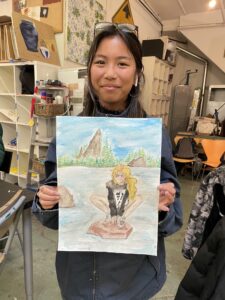 Student showing watercolor landscape painting.