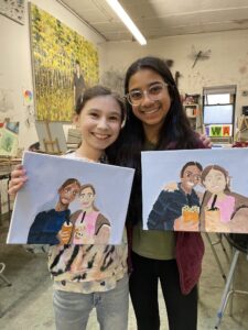 Two girls showing off their paintings.