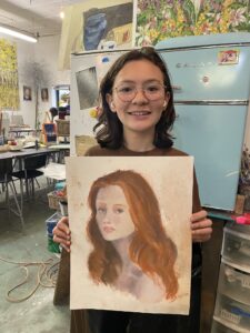 Girl proudly displays her pastel portrait.