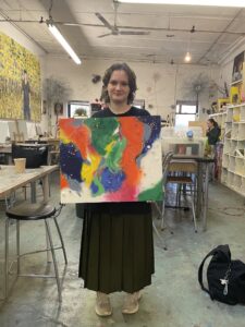 Student holding colorful mixed-media artwork.