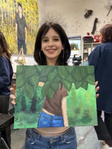 Girl proudly displays her leafy painting.