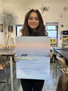 Girl holding sailboat sunset painting.