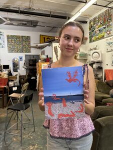 Woman holding beach scene print with dragon.