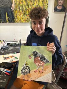 Teenager proudly displays bird painting.