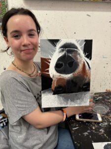 Girl proudly displays dog portrait painting.