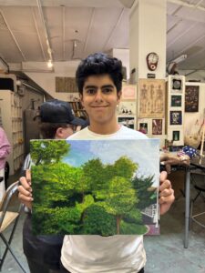 Teenager proudly displays his landscape painting.