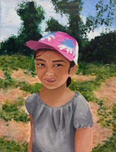 A young girl wearing a pink cap and gray dress outdoors.