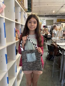 Young woman holding a patterned tote bag in a creative workspace.