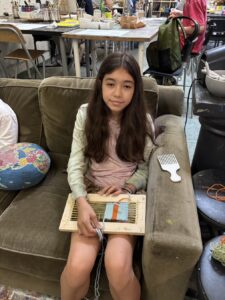 A young girl sitting on a couch playing a xylophone.