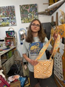 A woman holds two handcrafted wooden mirrors with geometric designs.