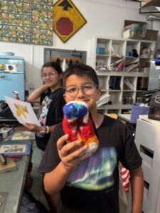 Boy happily holding a colorful stuffed toy in a creative classroom.