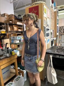 Young woman in casual outfit standing inside a cozy store.