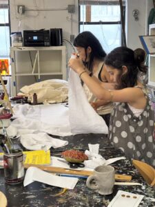Two girls crafting with white fabric in a cozy room.