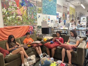 Four children sitting on a couch, eating snacks and chatting in a cozy room.
