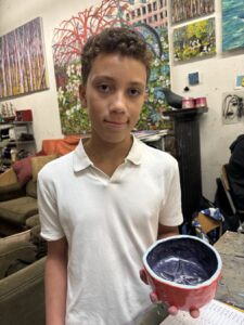 A boy in a white polo shirt holding a bowl of food indoors.