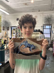 Young boy proudly holding a painting of a swimmer underwater.